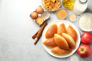 Photo of Tasty baked patties and ingredients on light grey table, flat lay. Space for text