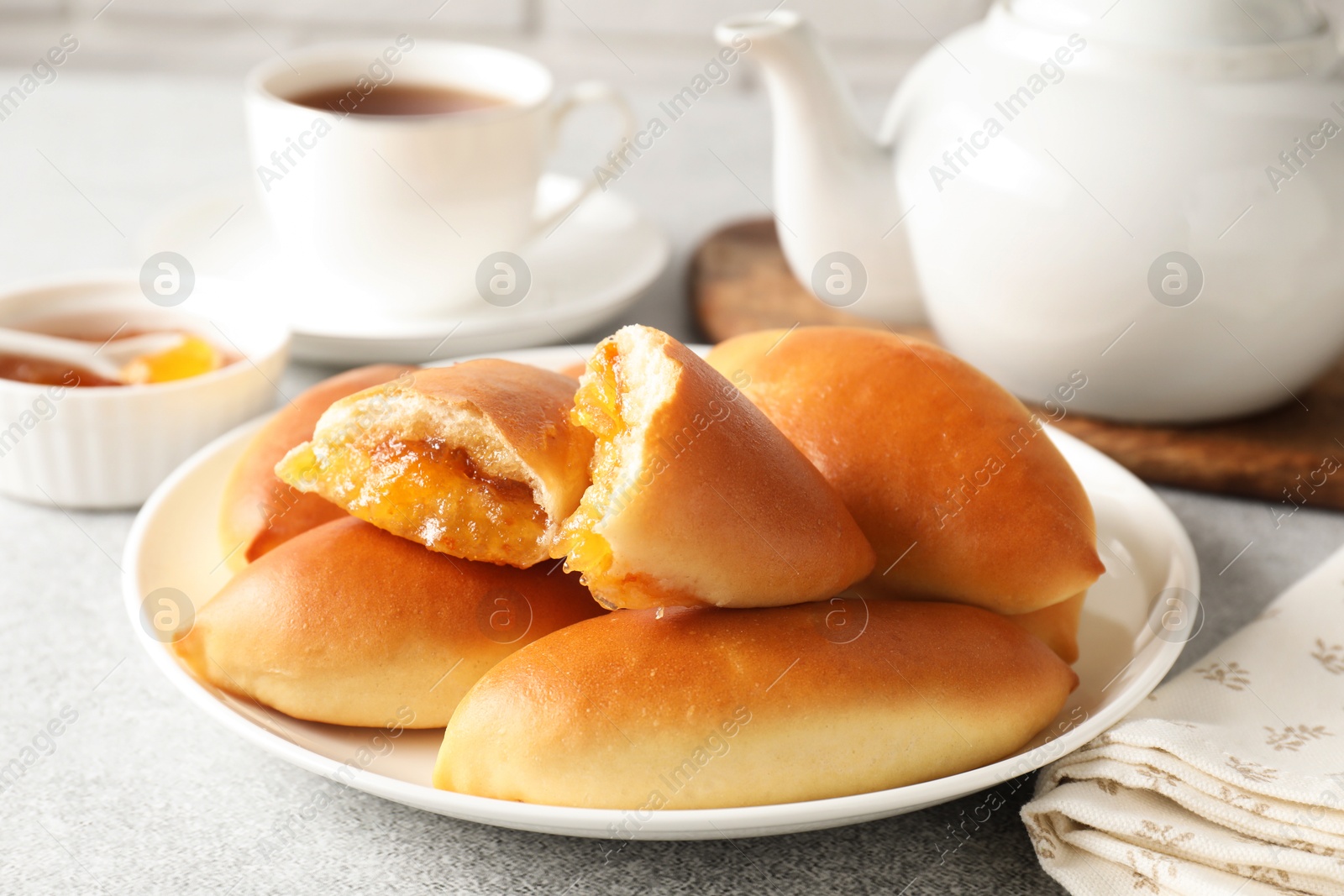 Tasty baked patties with orange jam on light grey table, closeup Photo of Tasty baked patties with orange jam on light grey table, closeup