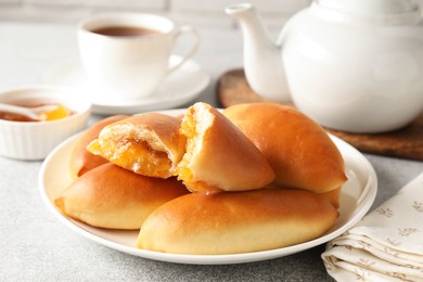 Photo of Tasty baked patties with orange jam on light grey table, closeup