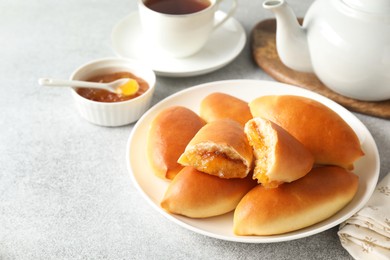 Photo of Tasty baked patties with orange jam on light grey table, closeup