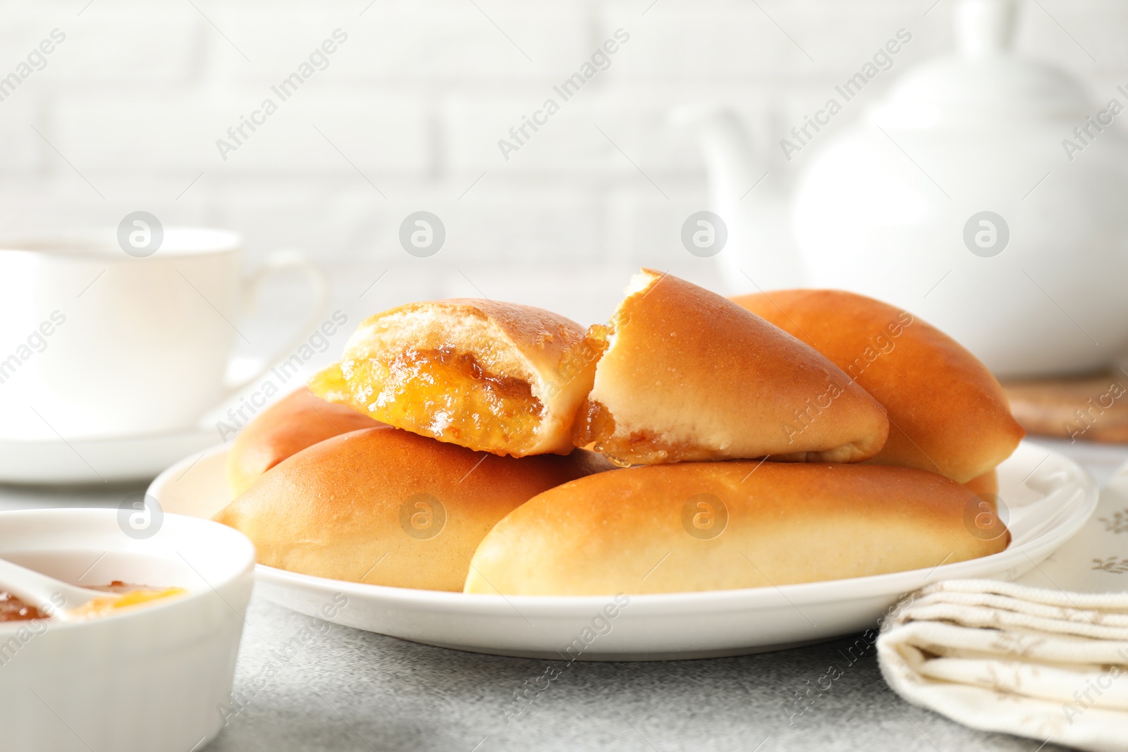 Tasty baked patties with orange jam on light grey table, closeup Photo of Tasty baked patties with orange jam on light grey table, closeup