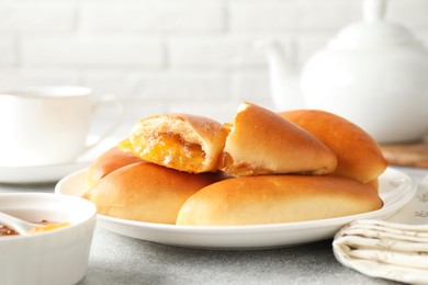 Photo of Tasty baked patties with orange jam on light grey table, closeup