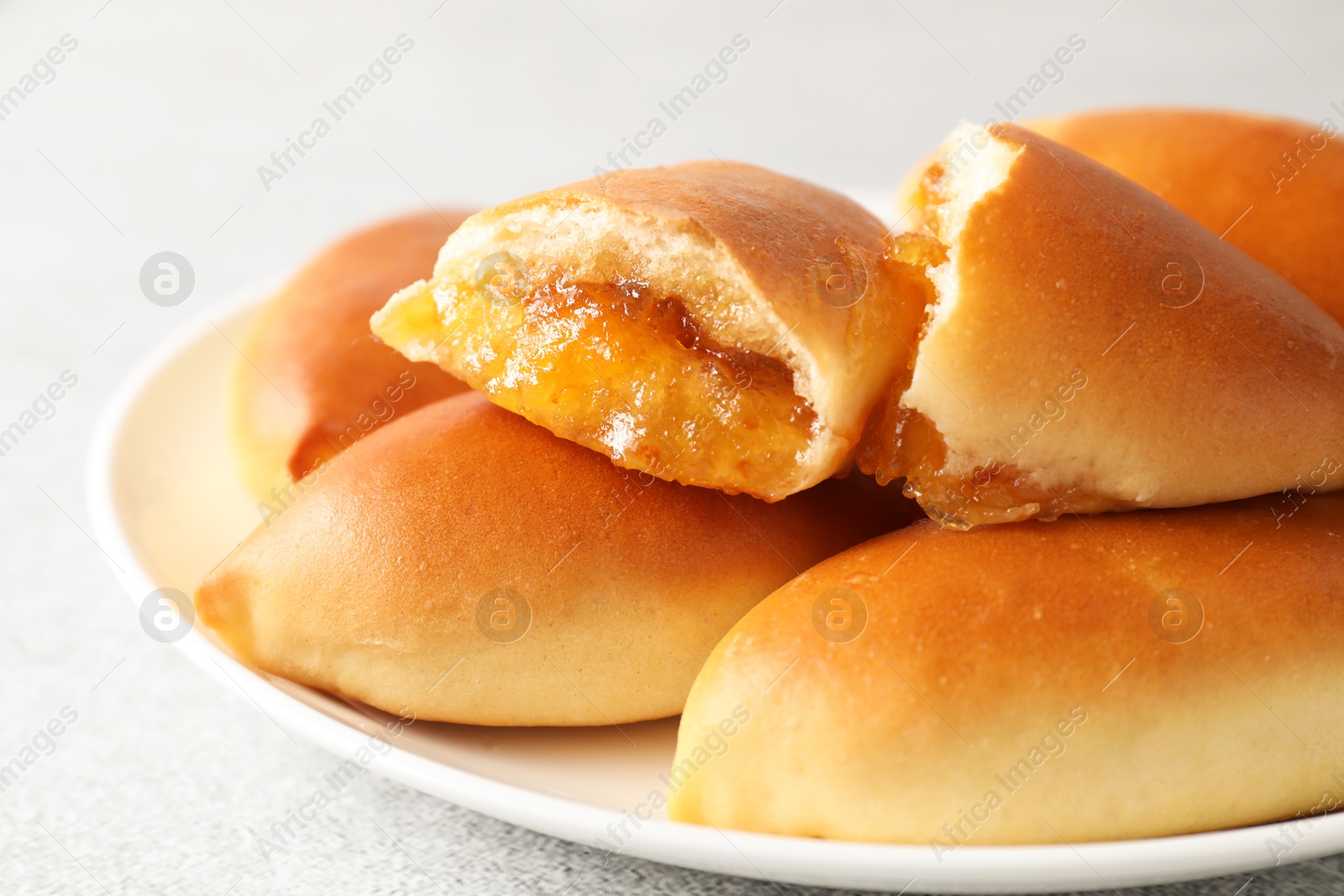 Tasty baked patties with orange jam on light grey table, closeup Photo of Tasty baked patties with orange jam on light grey table, closeup