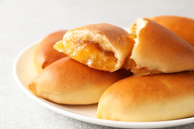 Photo of Tasty baked patties with orange jam on light grey table, closeup
