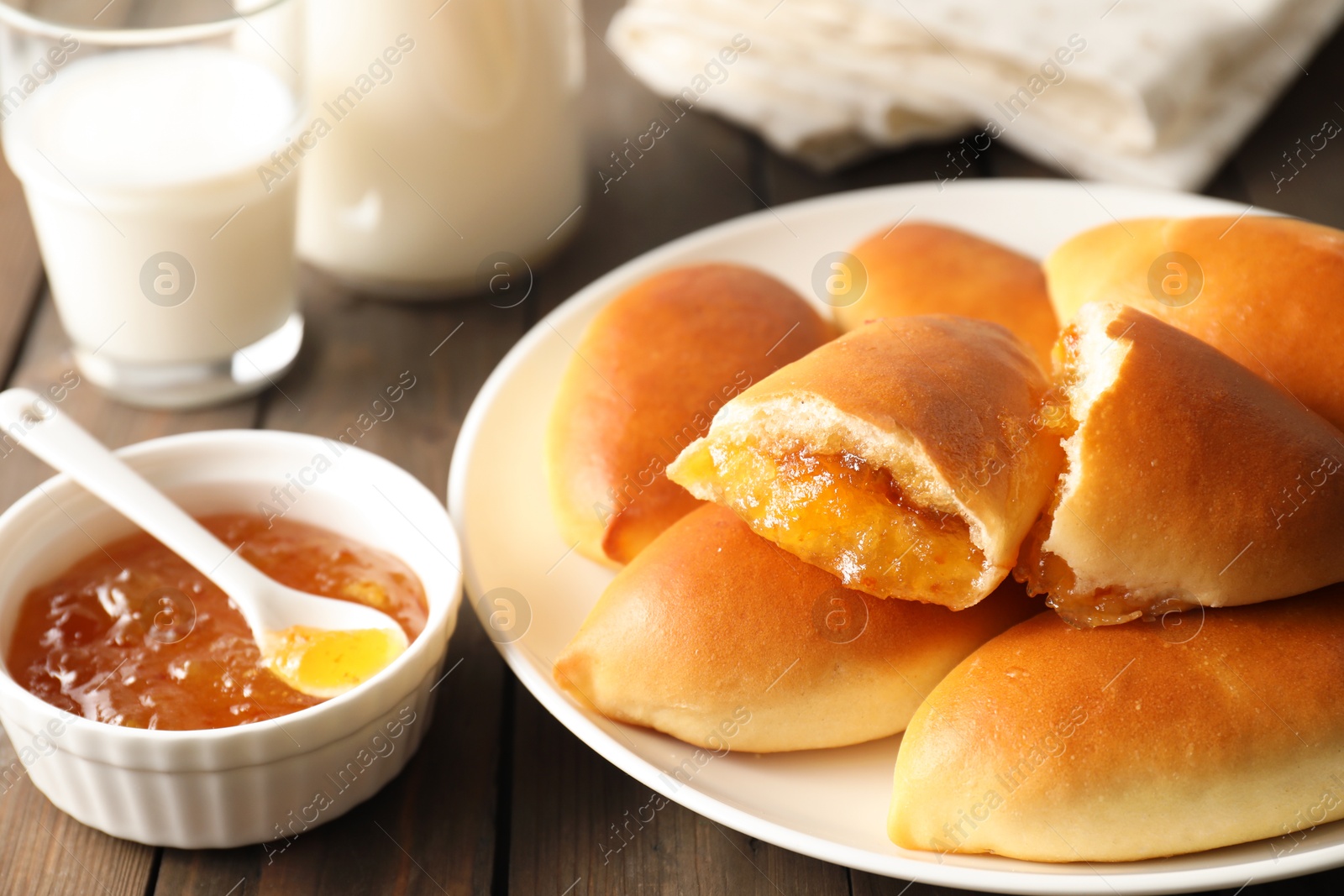 Tasty baked patties with orange jam on wooden table, closeup Photo of Tasty baked patties with orange jam on wooden table, closeup