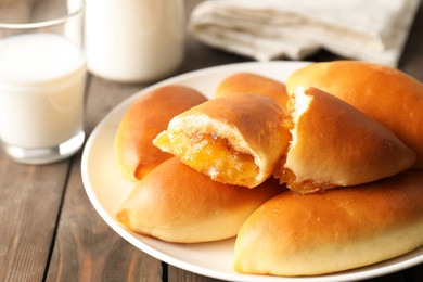 Photo of Tasty baked patties with orange jam on wooden table, closeup