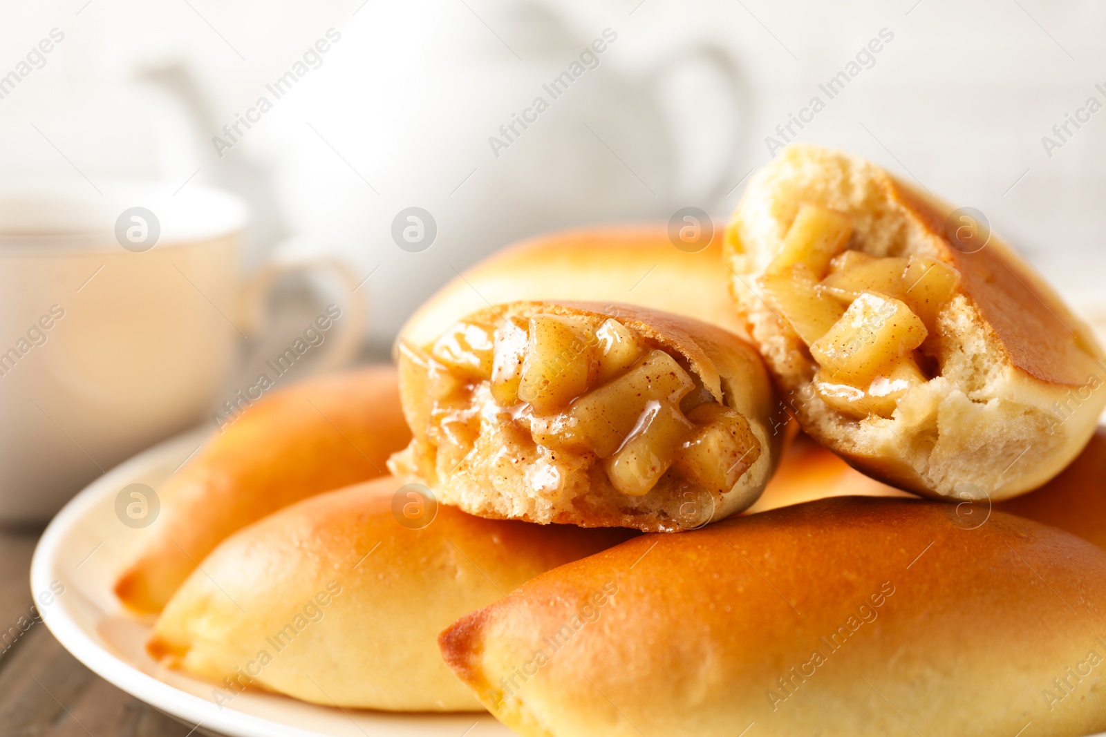 Tasty baked patties with apples on wooden table, closeup Photo of Tasty baked patties with apples on wooden table, closeup