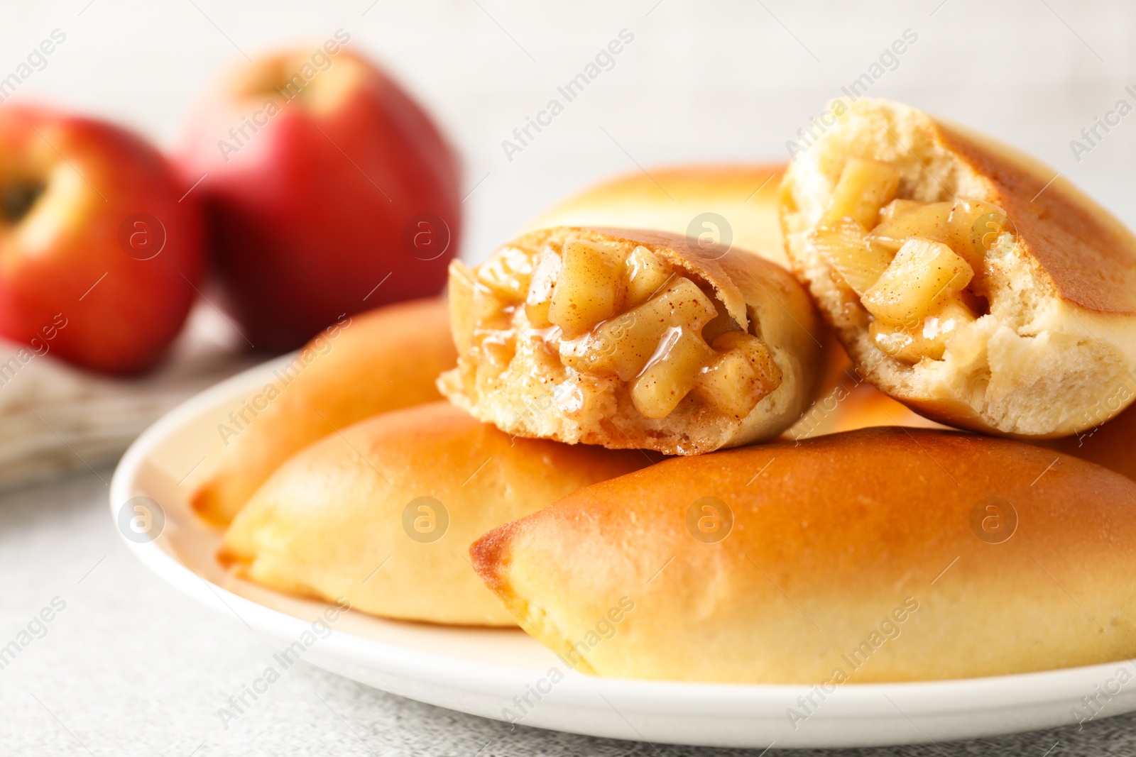 Tasty baked patties with apples on light grey table, closeup Photo of Tasty baked patties with apples on light grey table, closeup