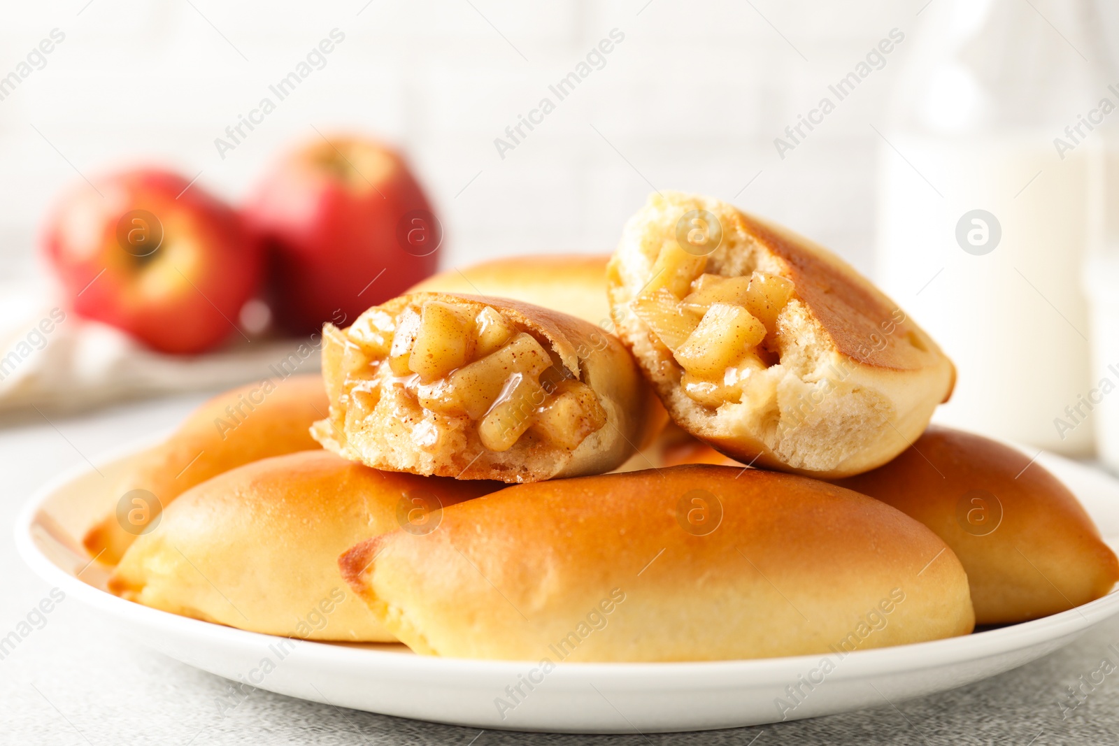 Tasty baked patties with apples on light grey table, closeup Photo of Tasty baked patties with apples on light grey table, closeup