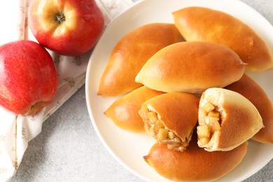 Photo of Tasty baked patties with apples on light grey table, flat lay