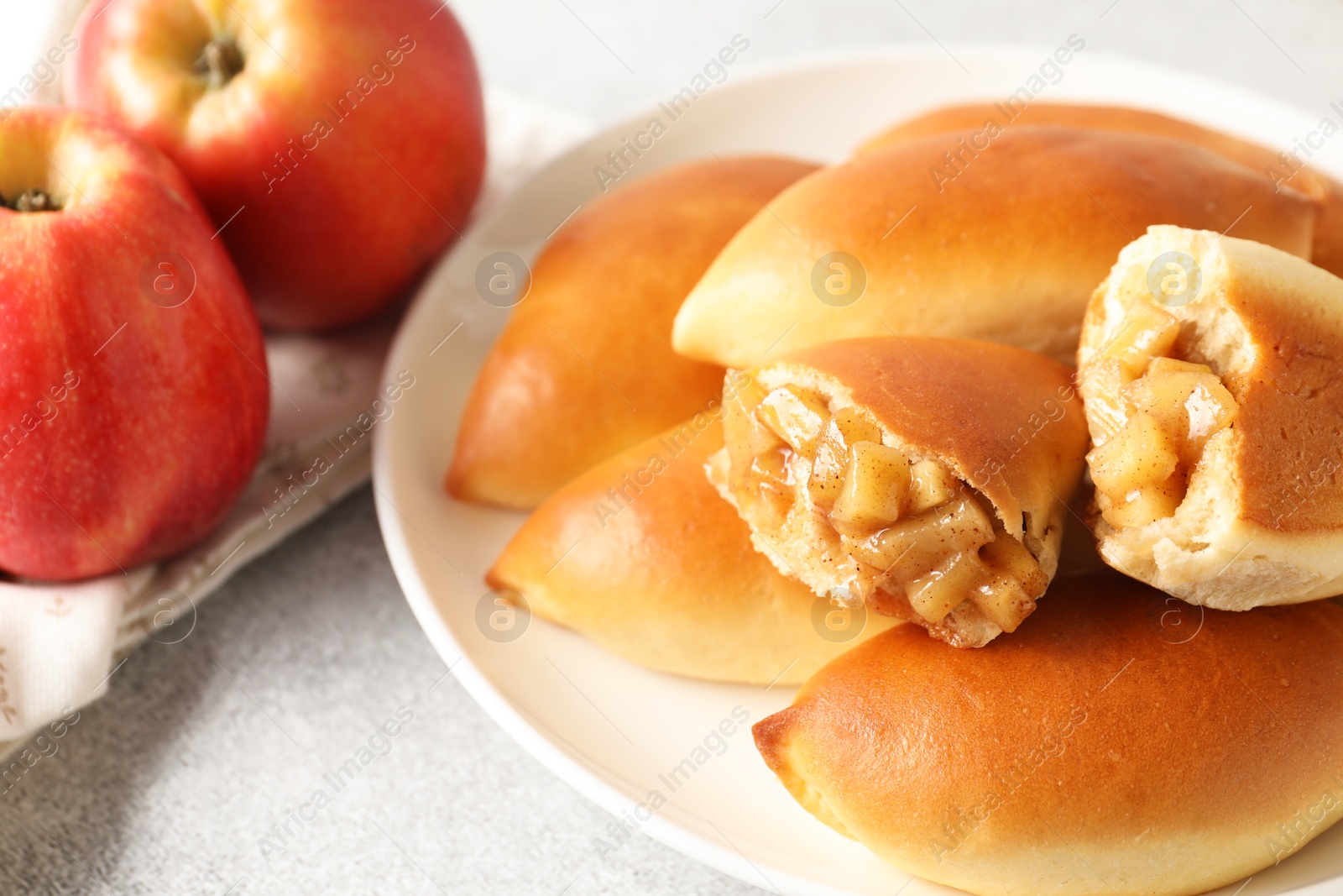 Tasty baked patties with apples on light grey table, closeup Photo of Tasty baked patties with apples on light grey table, closeup