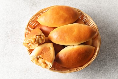 Photo of Tasty baked patties in wicker basket on light grey table, top view