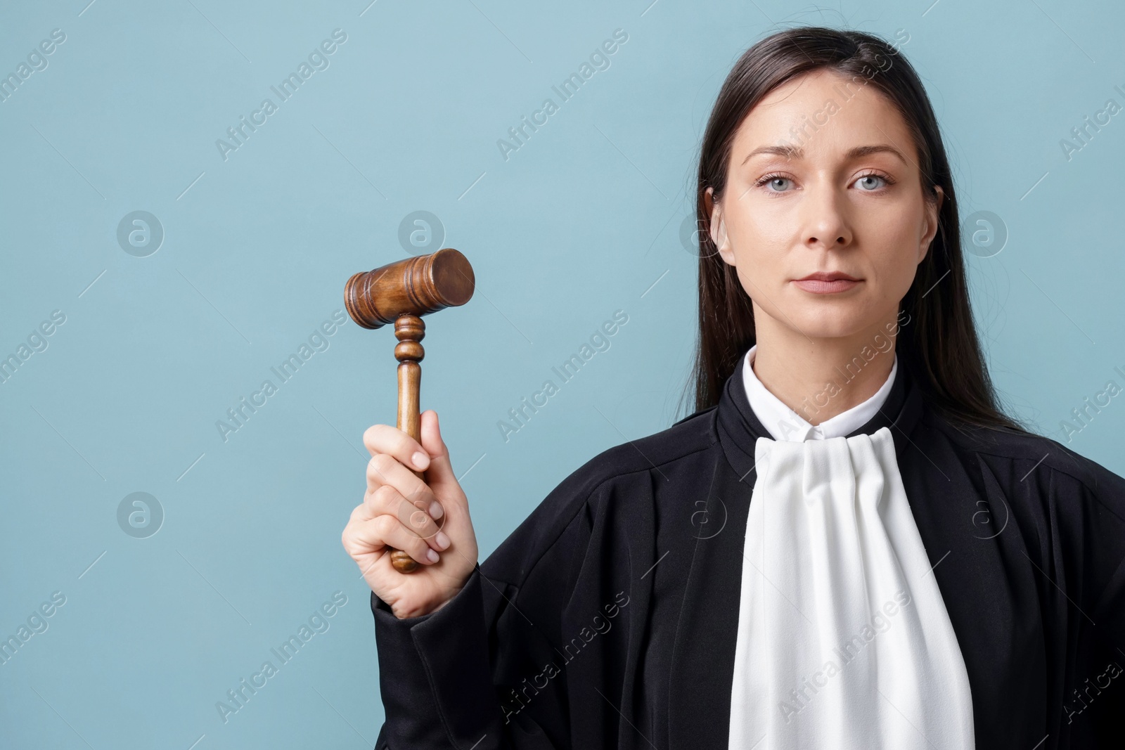 Judge with mallet on light blue background, space for text Photo of Judge with mallet on light blue background, space for text