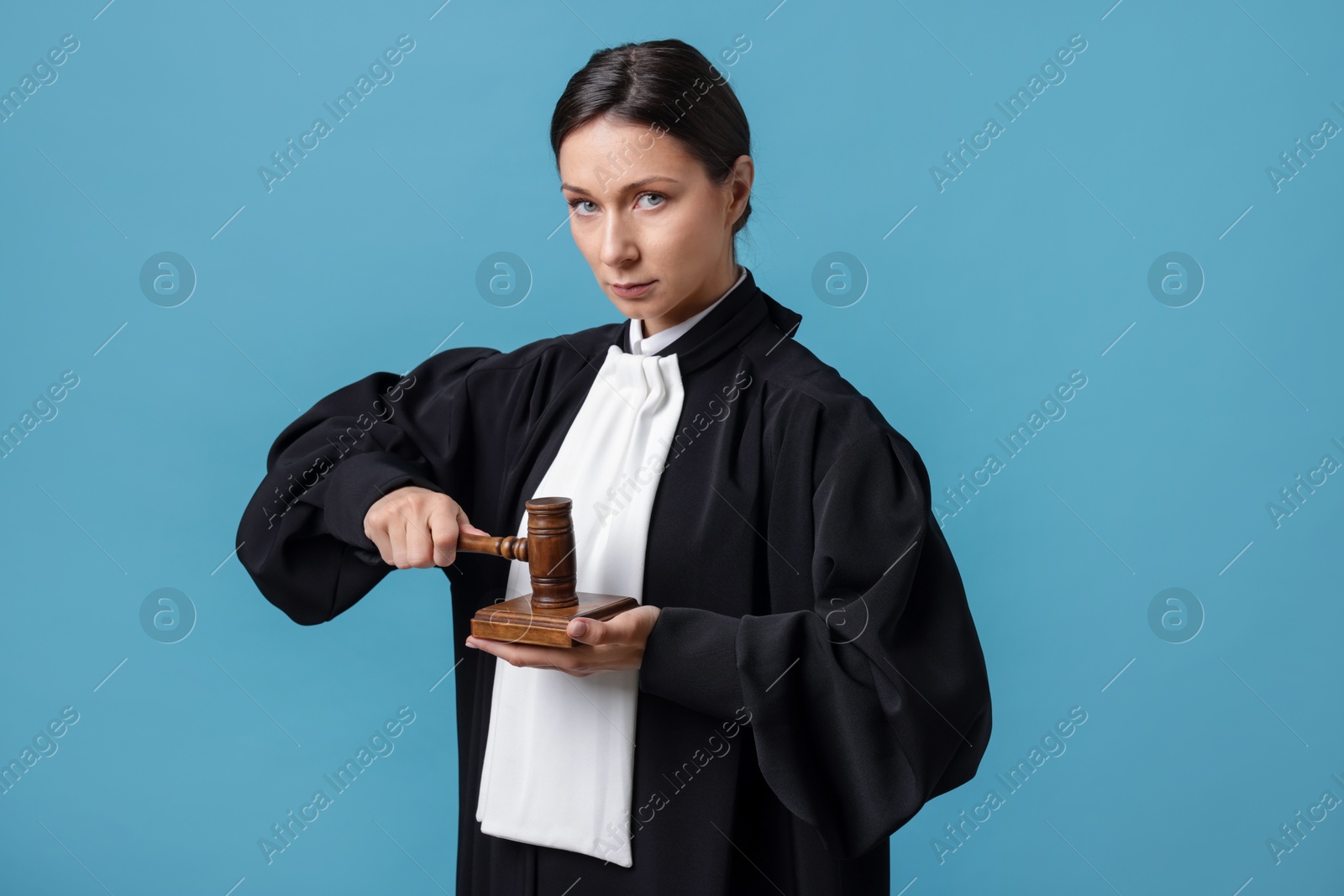 Judge with mallet and sound block on light blue background Photo of Judge with mallet and sound block on light blue background