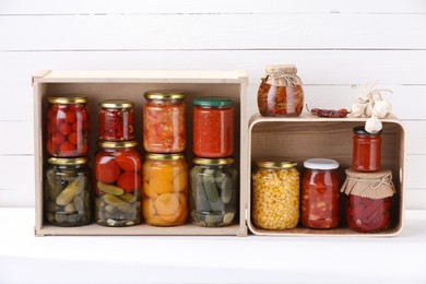 Photo of Many jars with different pickled products and ingredients on white table