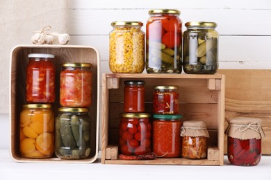 Photo of Many jars with different pickled products and ingredients on white wooden table