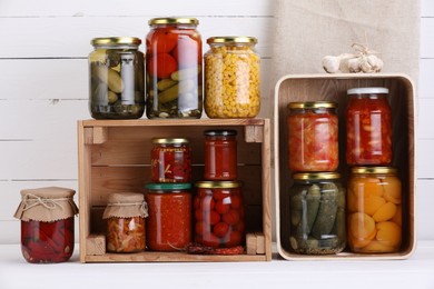 Photo of Many jars with different pickled products and ingredients on white wooden table
