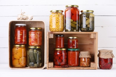 Photo of Many jars with different pickled products and ingredients on white wooden table