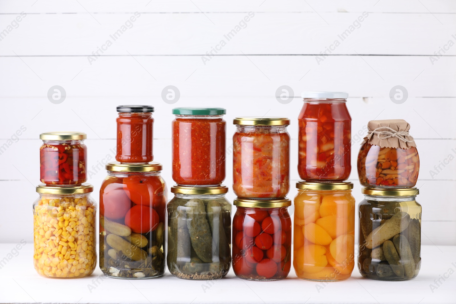 Many jars with different pickled products on white table Photo of Many jars with different pickled products on white table