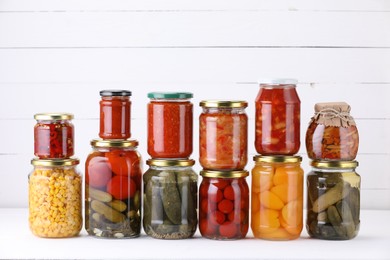 Photo of Many jars with different pickled products on white table