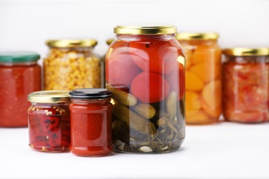 Photo of Many jars with different pickled products on white wooden table