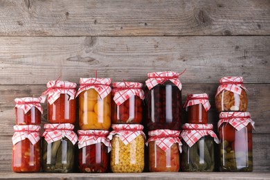 Photo of Many jars with different pickled products on wooden table