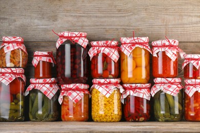 Photo of Many jars with different pickled products on wooden table