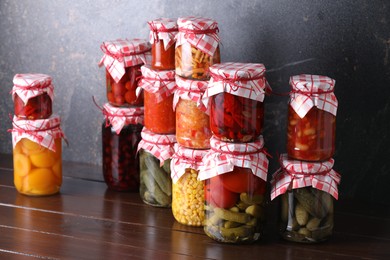 Photo of Many jars with different pickled products on wooden table