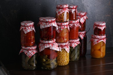 Photo of Many jars with different pickled products on wooden table