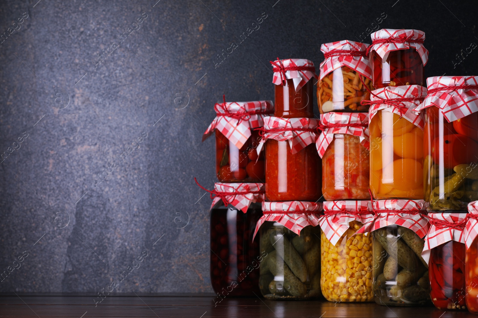 Many jars with different pickled products on wooden table, space for text Photo of Many jars with different pickled products on wooden table, space for text