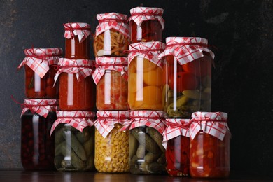 Photo of Many jars with different pickled products on wooden table