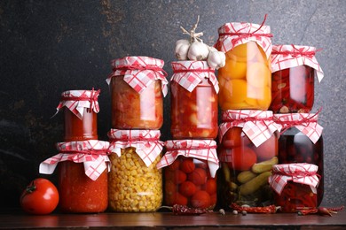 Photo of Many jars with different pickled products and ingredients on wooden table