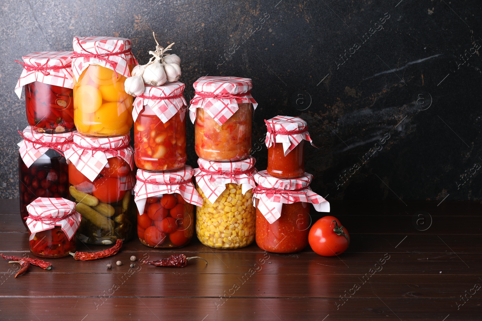 Many jars with different pickled products and ingredients on wooden table, space for text Photo of Many jars with different pickled products and ingredients on wooden table, space for text