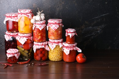 Photo of Many jars with different pickled products and ingredients on wooden table, space for text