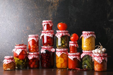 Photo of Many jars with different pickled products and ingredients on wooden table
