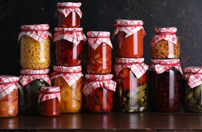 Photo of Many jars with different pickled products on wooden table