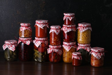 Photo of Many jars with different pickled products on wooden table