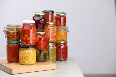 Photo of Many jars with different pickled products on light grey table, space for text