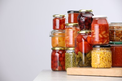Photo of Many jars with different pickled products on light grey table, space for text