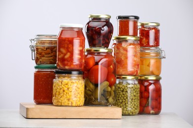 Photo of Many jars with different pickled products on light grey table