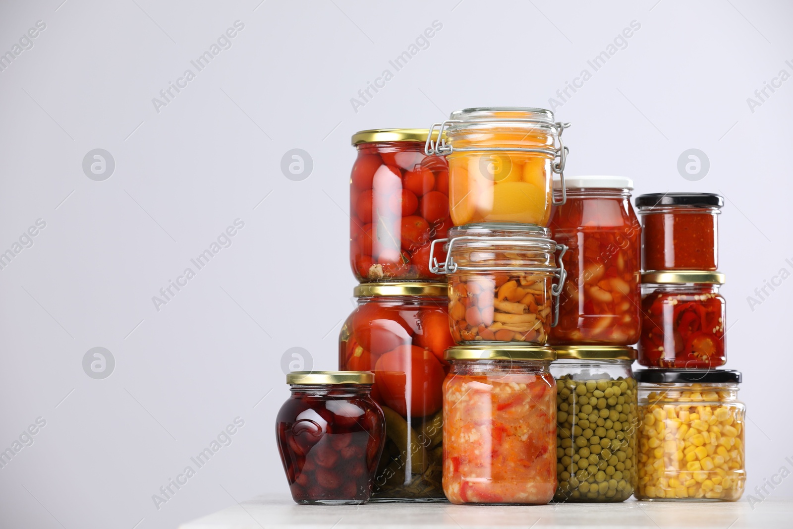 Many jars with different pickled products on light grey table, space for text Photo of Many jars with different pickled products on light grey table, space for text