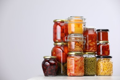 Photo of Many jars with different pickled products on light grey table, space for text