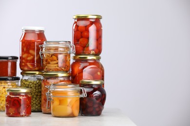 Photo of Many jars with different pickled products on light grey table, space for text