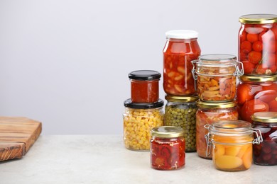 Photo of Many jars with different pickled products on light grey table, space for text