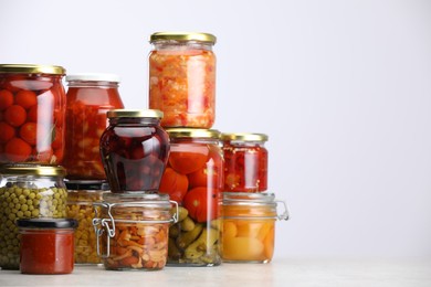 Photo of Many jars with different pickled products on light grey table, space for text
