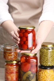 Photo of Woman with many jars of different pickled products, closeup