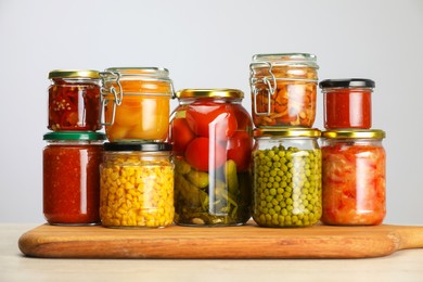 Photo of Many jars with different pickled products on table against light grey background