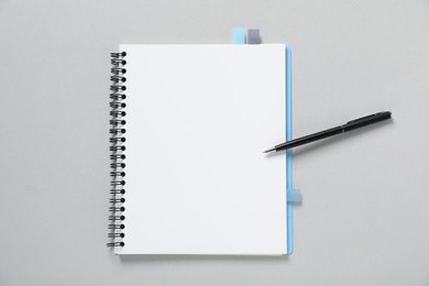 Photo of Open blank notebook with colorful stickers and pen on light grey background, top view