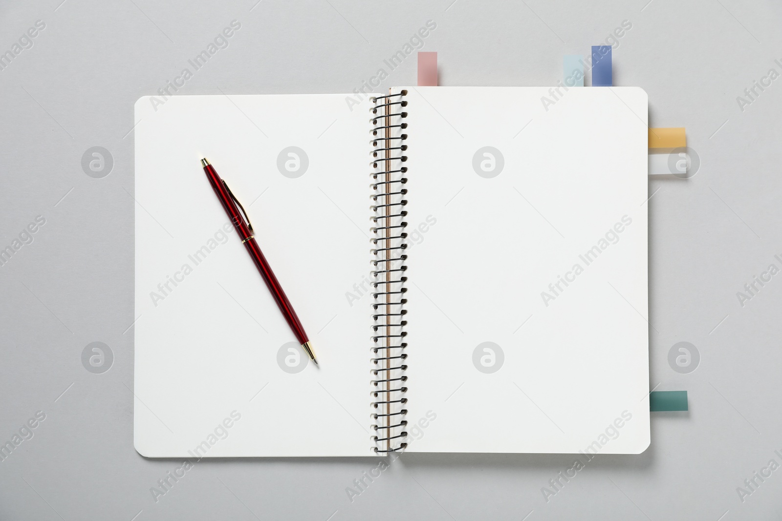 Open blank notebook with colorful stickers and pen on light grey background, top view Photo of Open blank notebook with colorful stickers and pen on light grey background, top view