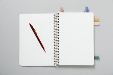 Photo of Open blank notebook with colorful stickers and pen on light grey background, top view